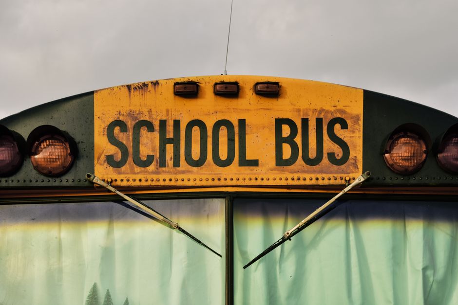 Detailed shot of a classic yellow school bus front with visible window and wipers.
